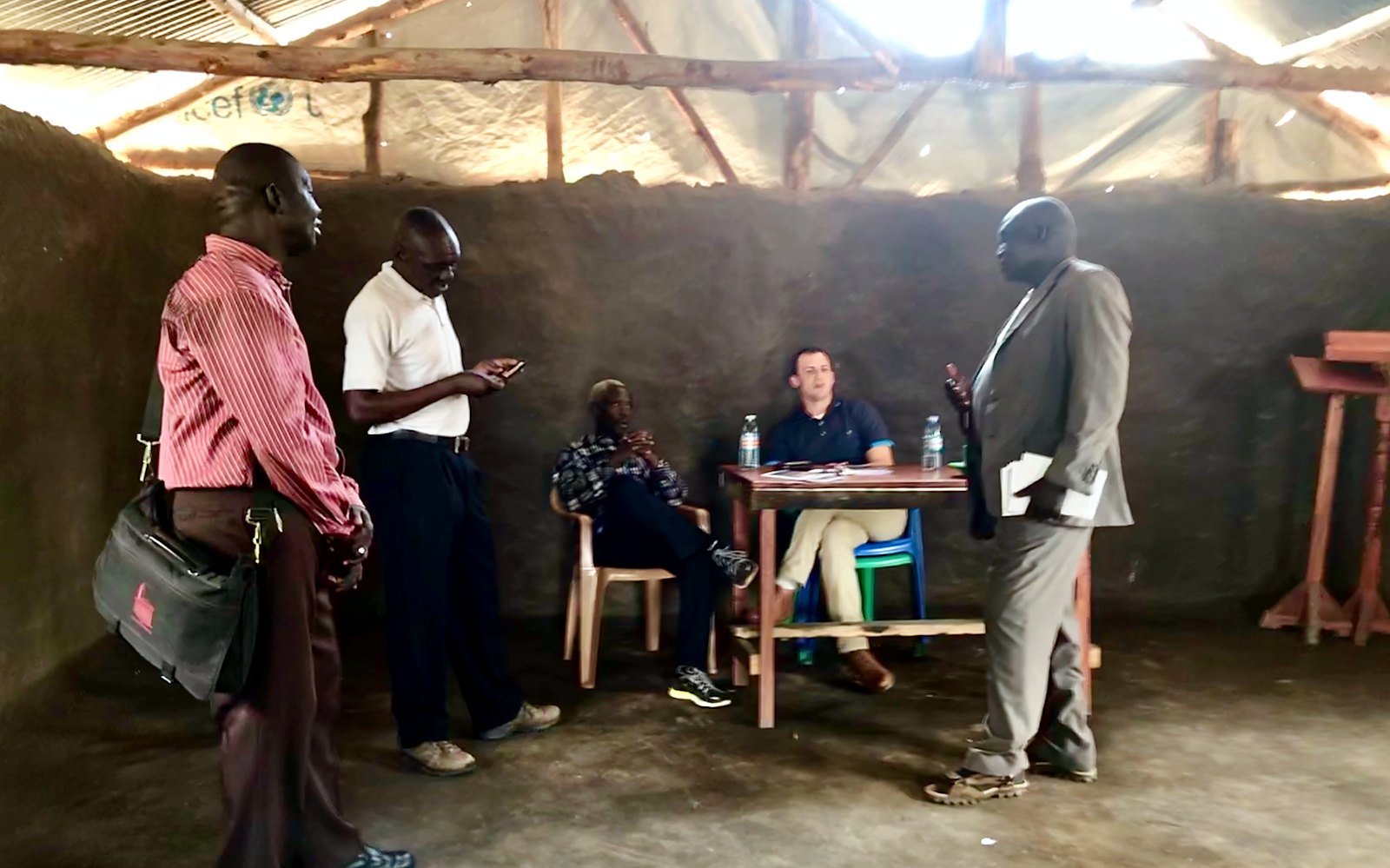 Brad Hobbs at a table in a mud hut in a refugee camp in northern Uganda